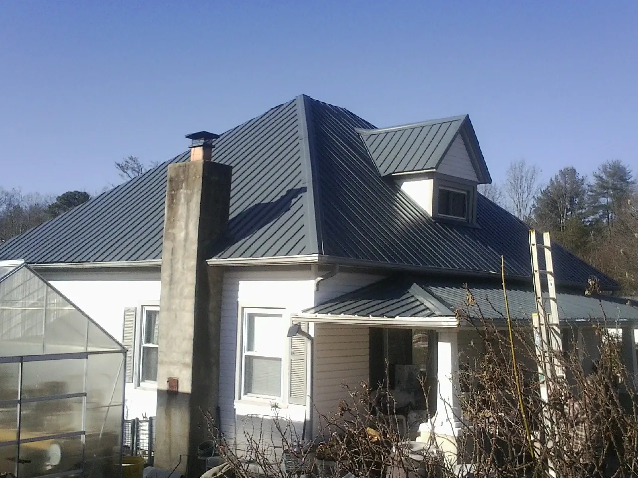 Dark blue standing seam metal roof on a white farmhouse with dormer — Slate & Tile Roof Repair by Roofing Brothers in Ashaway