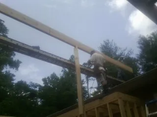 Carpenter setting a ridge beam over a new addition frame — Ice Dam Removal by Roofing Brothers in Ashaway
