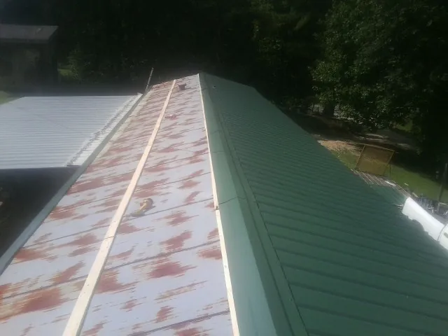 Old rusted panels beside newly installed green metal roofing — Wind Damage Roof Repair by Roofing Brothers in Ashaway