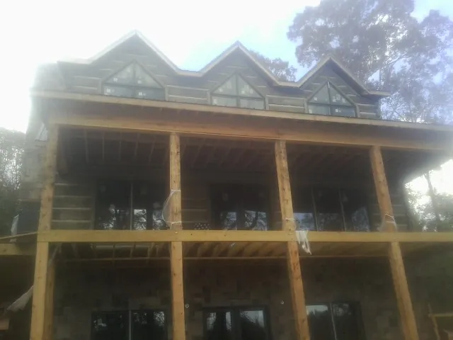 Dormers and porch framing on a large log home under construction — Roof Coating work by our crew in Ashaway