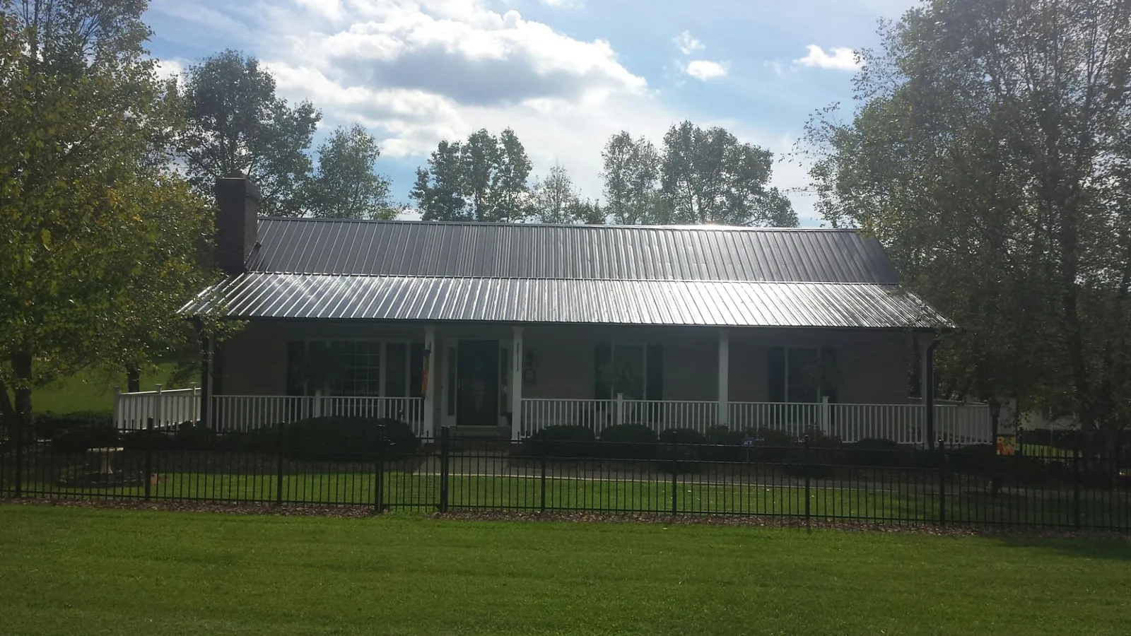 Gray metal roof on a brick ranch with a full width front porch — Gutter Guard Installation work by our crew in Ashaway