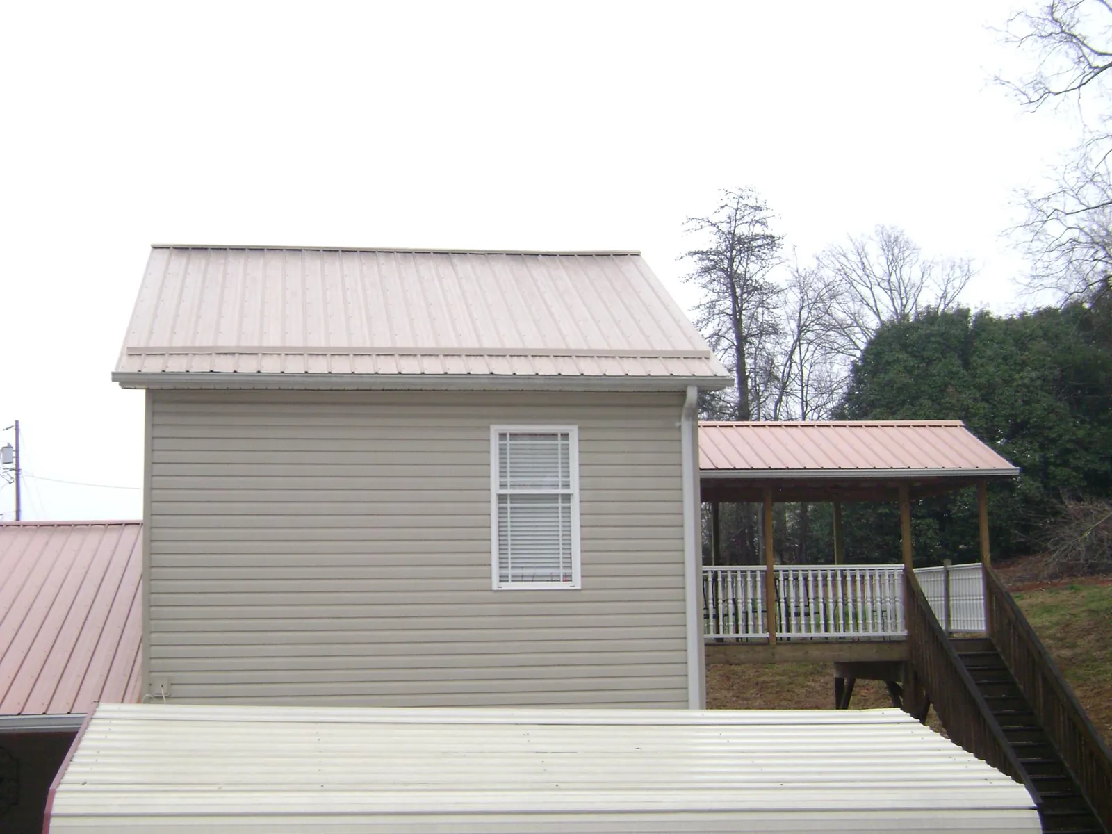 Tan metal roofs on a two story addition and attached porch, from a Roof Replacement job in Ashaway