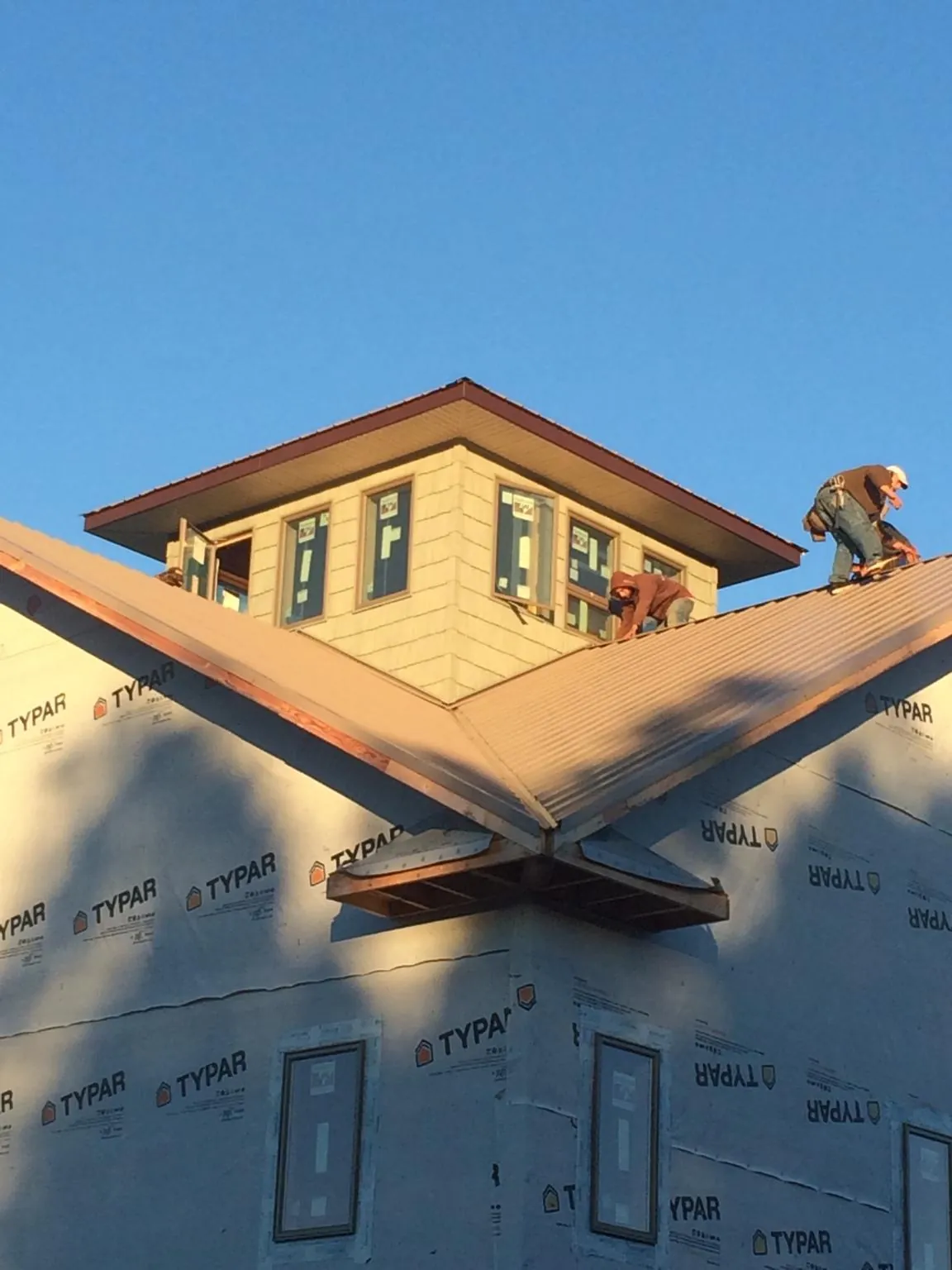 Roofers working around a rooftop cupola on a new metal roof at sunset — Roof Waterproofing in Ashaway by Roofing Brothers